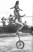 Nude shoulder rides on a tall unicycle 1960s