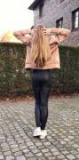 Backside view to a young blondie in tight black leather leggings