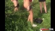 Girl bent over peeing in the grass at a festival