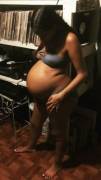 Young expecting mother looking at her fully extended belly