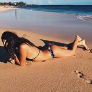 Laying in the sand under the afternoon sun, coyly looking away