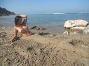 Topless babe half-buried in the beautiful beach