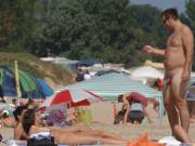 Nude beach fun. He's taking a picture and she doesn't seem to care.