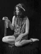 Portrait of model Eva Reitspiesova, naked but for a large collection of cotume jewelry and necklaces, as she sits against a dark background, 2015.