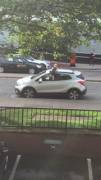 Mother chats on phone while child climbs out of car