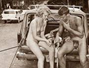 A couple sitting on a hood of a car.